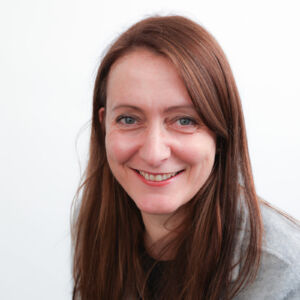 AA head and shoulder image of Ali Jones - a white woman with dark long hair - smiling at the camera 