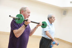 Image of 2 prehab4cancer participants in a gym using weights.