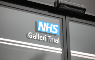 A window of a trials unit shows the NHS Galleri Trial logo attached to the outside