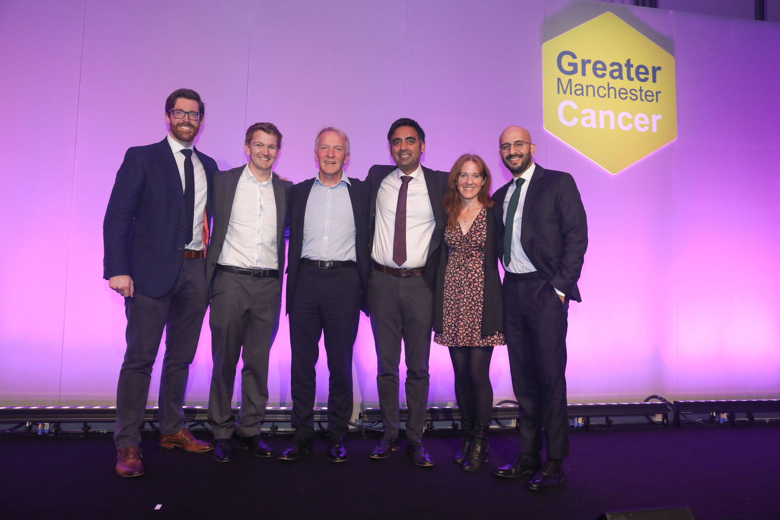 Five men and one woman on stage at the GM Cancer Awards with their arms around each our