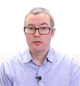 Dr Liam Hosie a white man wearing small glasses and a blue shirt