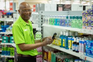 An Asda employee in lime green uniform scanning toothpaste and mouth wash which has NHS advice included on it