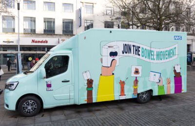GMCancer_Nov28th_2024_0006 A bright blue van with cartoon imagery on the site. The text reads; join the bowel movement