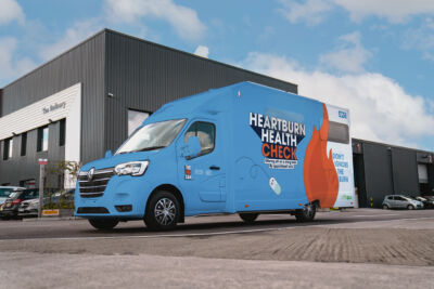 Heartburn health check van image 1 A blue Heartburn Health Check van parked outside a modern building.