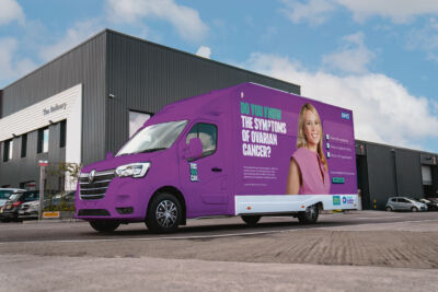Outreach Ovarian Cancer View 1 A bright purple van with a photo of the late Dianne Oxberry on the side and the words "Do you know the symptoms of ovarian cancer?"