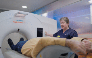 A medical professional is operating a Siemens Healthineers MRI machine, with a patient undergoing a scan.