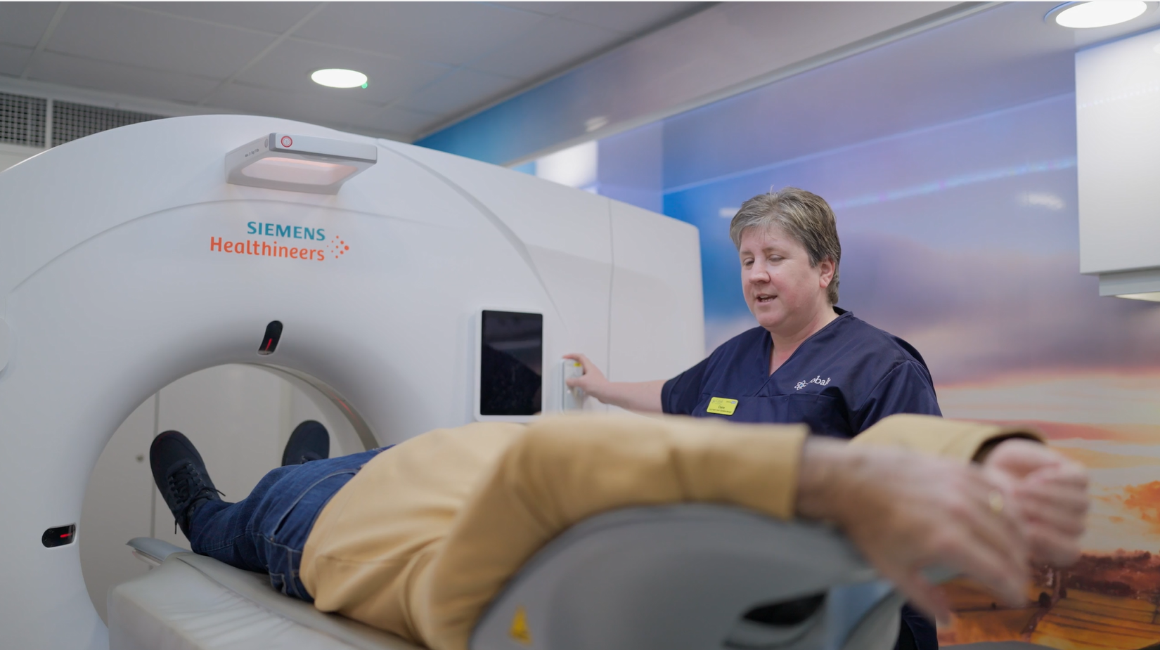 A medical professional is operating a Siemens Healthineers MRI machine, with a patient undergoing a scan.