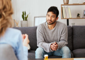 A man sits on a sofa and talks to a counsellor