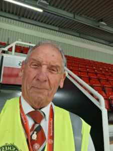 Tom safety steward old trafford Tom - an older white man with grey hair - wears a luminous steward's jacket and stands in the stadium at Manchester United's ground