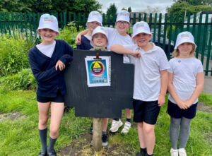 A group of six primary school pupils in sun hats hold their 'sun safe schools' accreditation certificate
