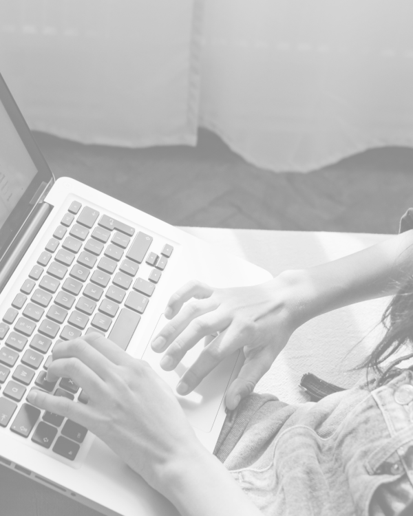 a black and white photo of some hands on a laptop keyboard
