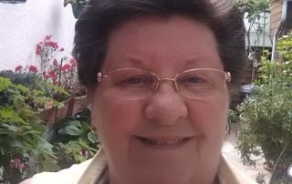 A head and shoulders image of Lesley Scott a woman with short dark hair and glasses outdoors