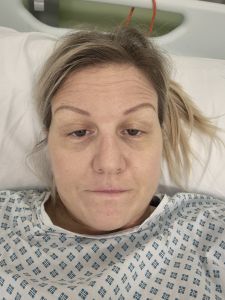 Alicia - a white woman with blonde hair in a hospital gown lying down during her treatment