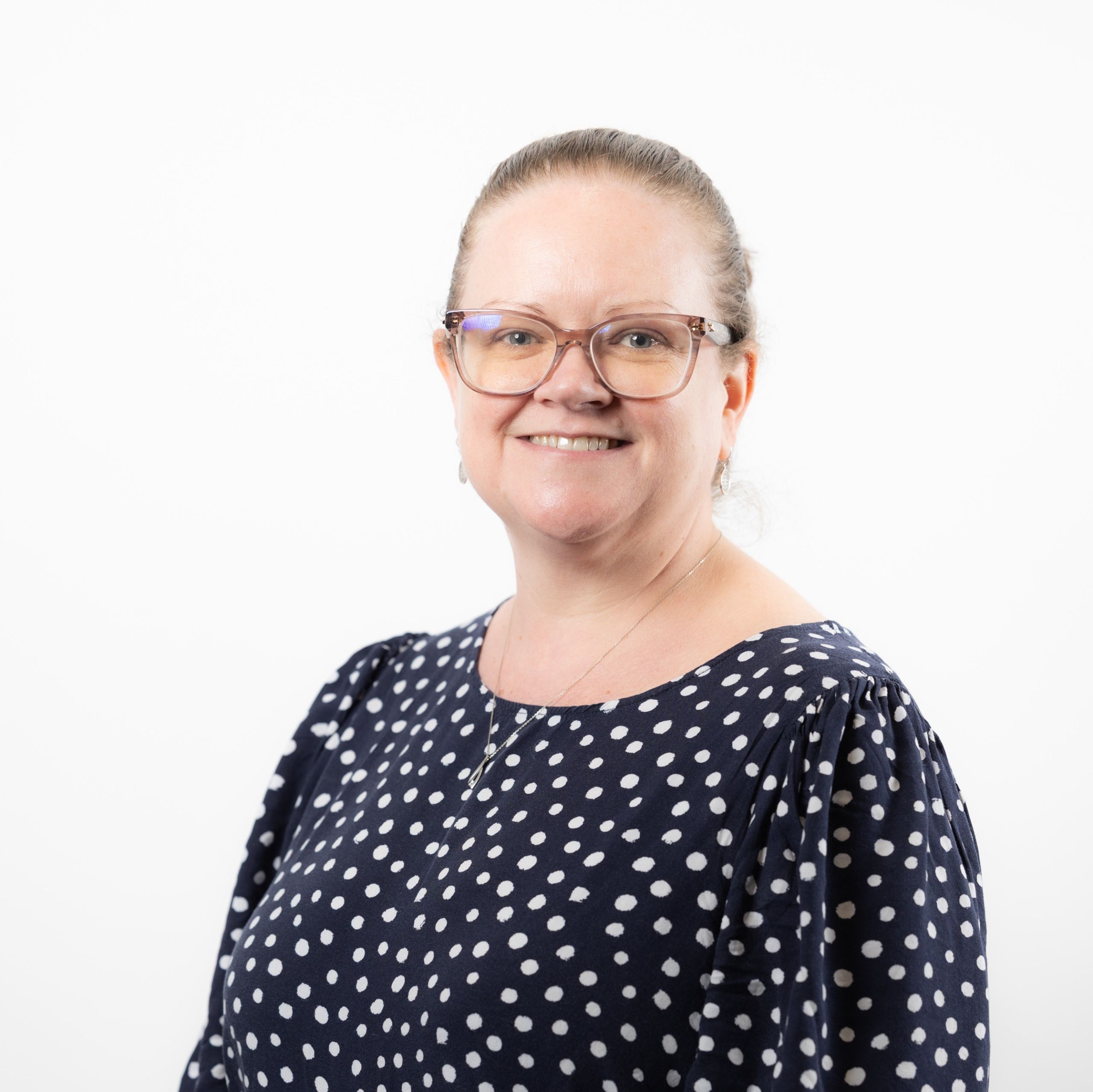 Louise Brown, Clinical Lead for Lung Cancer at Greater Manchester Cancer Alliance smiling and wearing glasses and a patterned top.
