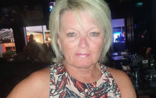 Sue, a white women with blonde hair and a short sleeve top