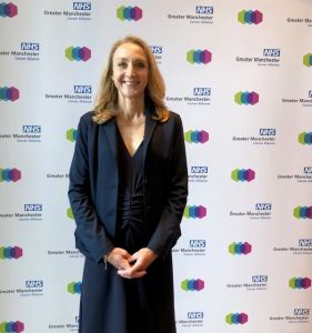 Runner Paula Radcliffe standing in front of the Greater Manchester Cancer Alliance logos