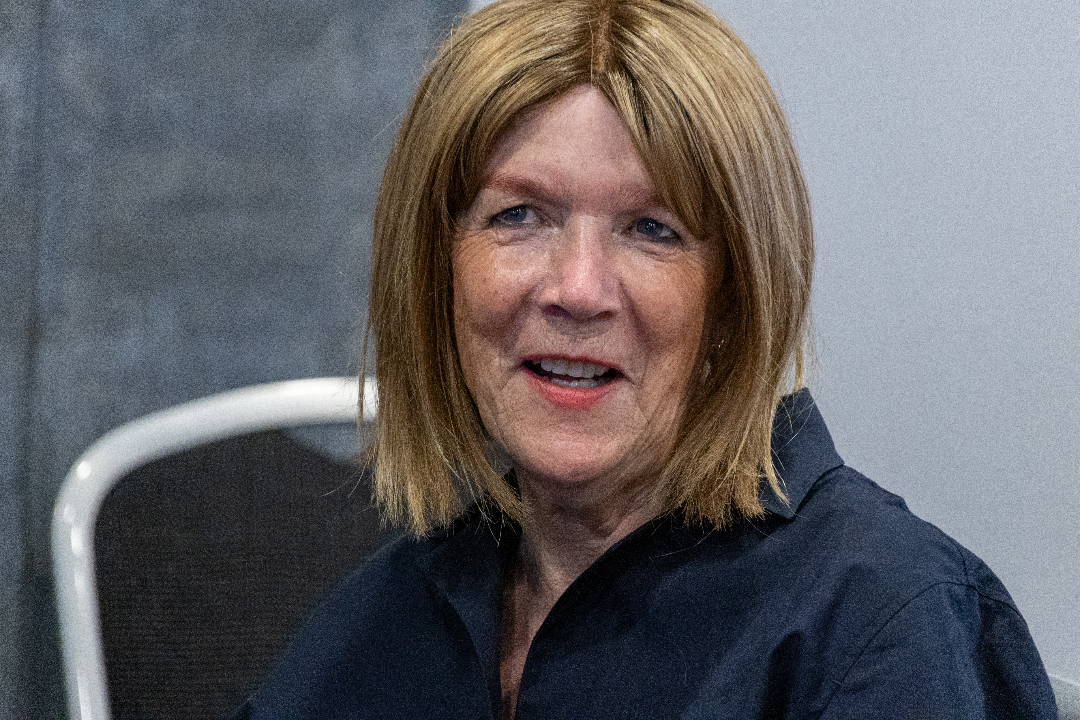 27 A woman smiling while listening to a speaker during a conference session.
