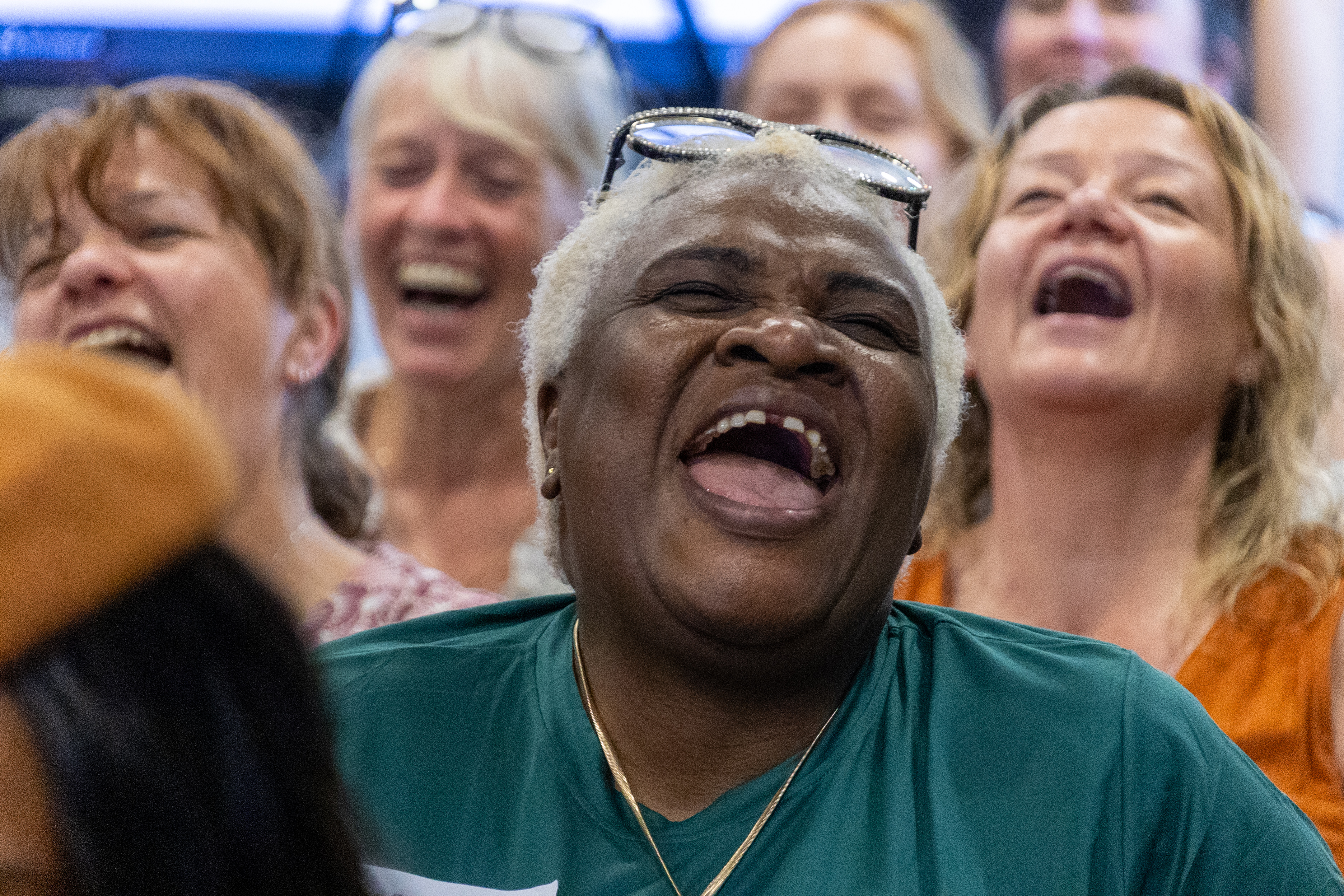 29 Close up of a woman smiling out loud at a conference with other delegates in the background laughing too