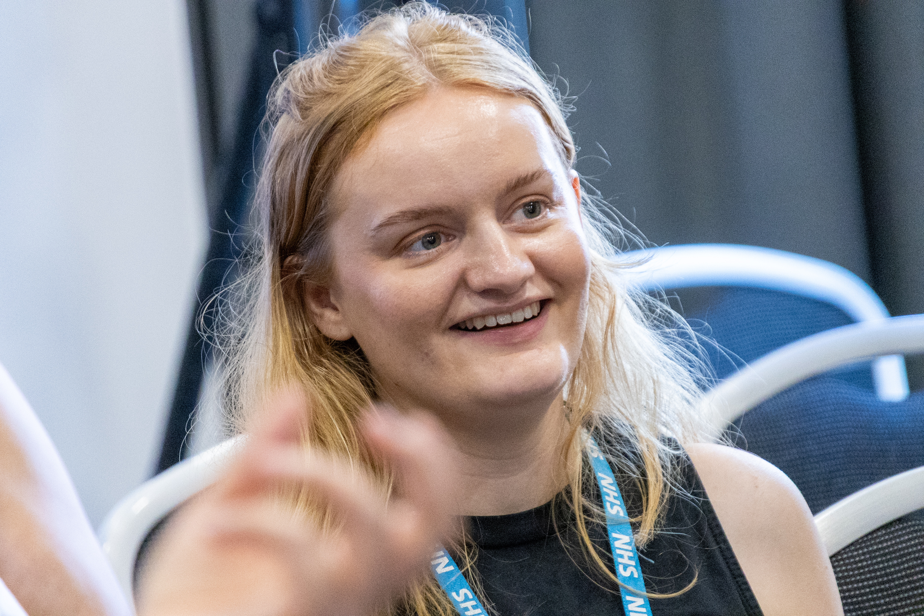 33 Rebecca from the Greater Manchester Cancer Voices Community team wearing a NHS lanyard sat down at the conference smiling