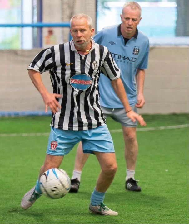 Pete Smart in black and white shirt playing football with his Manchester team.