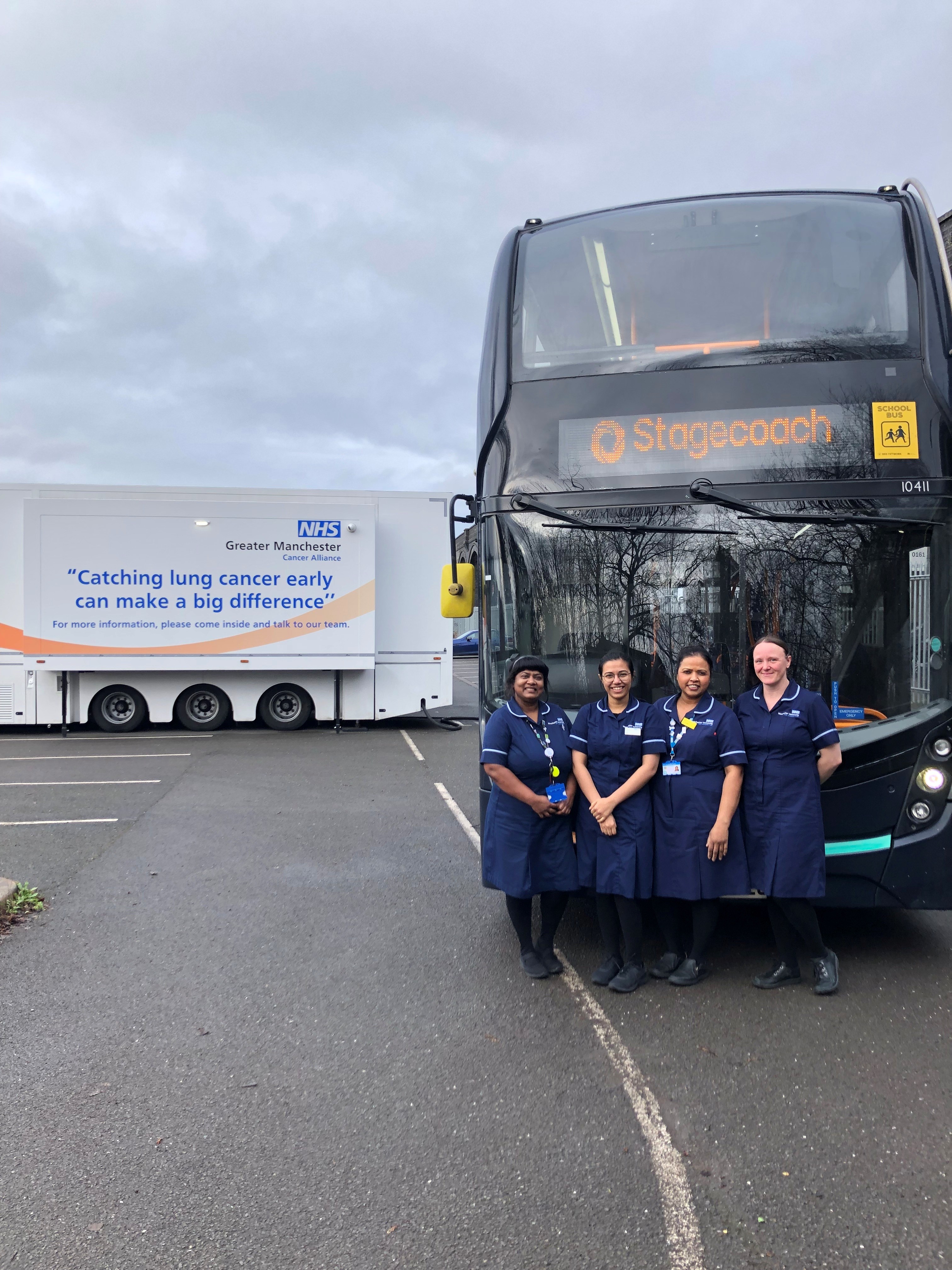 Four nurses stand in a car park in front of a Stagecoach bus and an NHS mobile clinic with the words Finding lung cancer early can make a big difference written on the side